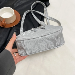 Silver metallic bow handbag with textured finish shown from a stylish side angle