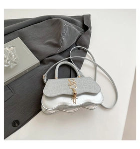 Detail of silver crossbody bag featuring scalloped edges and gold tassel metal buckle