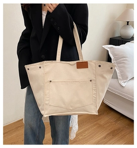Détail du sac cabas en toile crème avec poche géométrique et boutons pressions