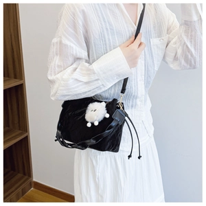 Close-up of black pleated shoulder bag featuring a cute white plush monster pendant