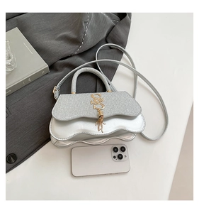 Silver mini crossbody bag with wavy cloud base and phone for size comparison reference