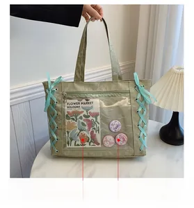 Detail of light green ita bag with large transparent PVC pocket and silk ribbon bows