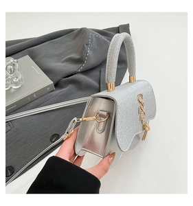 Silver metallic crossbody bag with glitter finish and decorative wave flap design