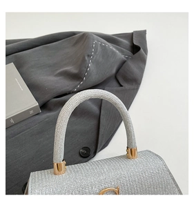 Close-up of silver glitter crossbody bag with golden horseshoe buckle and round handle