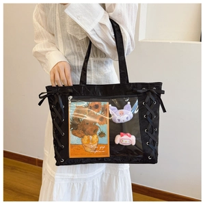 Detail of black ita bag with ribbon lace-up sides and transparent PVC window for dolls