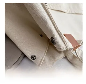 Gros plan sur le fermoir magnétique et la garniture en cuir marron du sac en toile