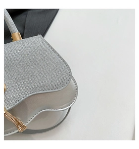 Macro detail of silver sequined saddle bag with golden fringe and metallic hardware