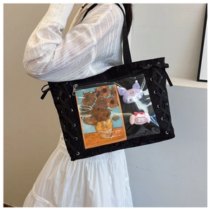 Detail of black tote bag with transparent PVC window displaying plush dolls and ribbons