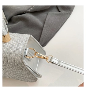 Macro shot of silver sequin bag detail showing gold hardware and textured shoulder strap