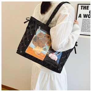 Detail of black ita-bag featuring large clear window with ribbon laces and side ties