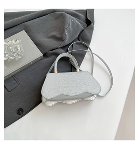 Detail of silver textured square handbag with unique wave-cut flap and metal finish
