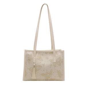 Sac fourre-tout beige avec broderie papillon dorée et breloque gland sur fond blanc
