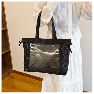 Detail of black ita bag tote with clear window and ribbon side ties worn by model