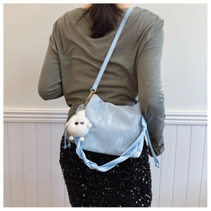 Detail of light blue pleated shoulder bag with knotted handle and plush monster charm