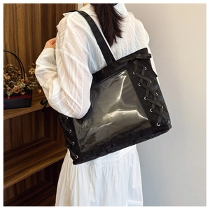 Lace-up ribbon detail and transparent PVC window on a black ita bag shown in use