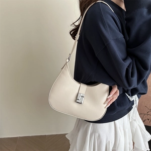 Creamy white half-moon hobo bag with silver geometric buckle shown on model shoulder