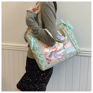 Close-up of mint green ita bag featuring ribbon bows and a clear display window