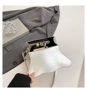 Interior view of silver crossbody bag showing storage for phone, perfume and lipstick