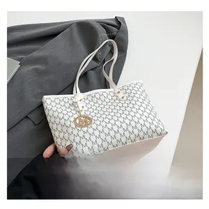 Detail of white leather tote with gray M pattern and gold metal letter charm