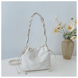 Detail of cream white bucket bag featuring woven handle and soft drawstring pleats