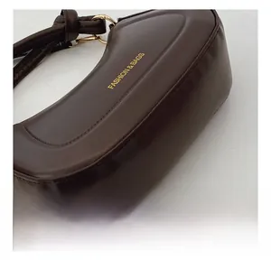 Detail view of precise stitching and gold hardware on a dark brown leather handbag