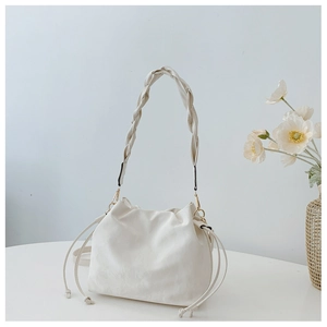 Detail of off-white drawstring bucket bag with woven handle and elegant texture