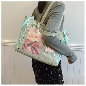 Detail of mint green ita bag with clear PVC window and cross-tied blue ribbons