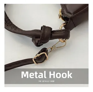 Detail of dark brown leather handbag featuring golden hardware hooks and stitching