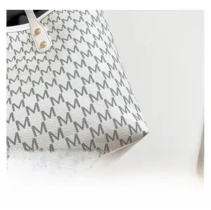 Detail of premium white leather tote bag with gray M-letter print and gold rivet hardware