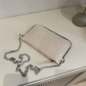 Minimalistische gewebte beige Kettentasche und Clutch auf einem sauberen Schreibtisch