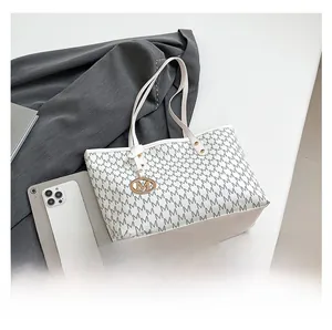Detail view of M-letter pattern on cream tote bag with golden metallic pendant