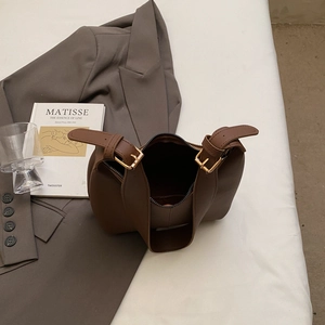 Large dark brown PU leather tote bag with gold hardware shown in a minimalist setting