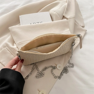 Minimalistische beige gewebte Umhängetasche mit Metallkette und Reißverschluss auf Blazer