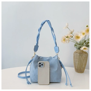 Light blue bucket bag with textured pattern and thick woven handle shown next to a phone