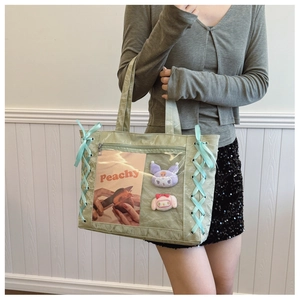 Detail of light green tote bag with blue ribbon lacing and clear front pocket