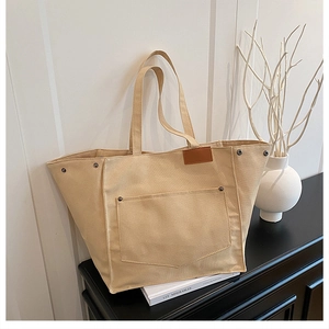 Détail du sac cabas en toile montrant la poche, les rivets et l'étiquette en cuir