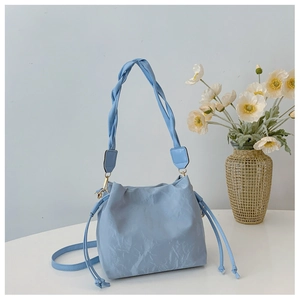 Close-up of light blue drawstring bucket bag with woven handle and textured finish