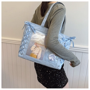 Detail of light blue ita bag showing ribbon bows and transparent window with badges