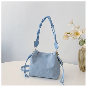 Detail of light blue bucket bag with pleated PU leather texture and woven handle design