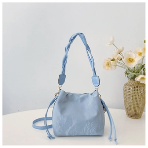 Detail of light blue drawstring bucket bag with marble texture and woven strap