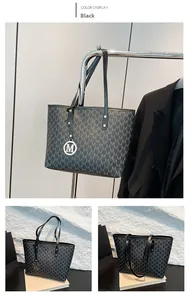 Detail of black tote bag featuring M-letter pattern with a metallic charm and leather strap