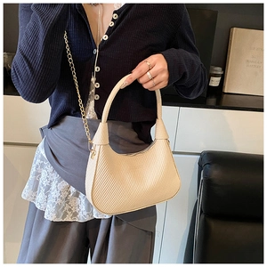 Detail of cream woven hobo bag with gold chain strap and textured fabric surface
