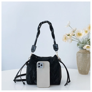 Detail of black drawstring bucket bag with pleated texture and leather braided strap
