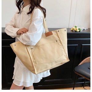 Détail du sac cabas en toile montrant la grande poche avant avec rivets renforcés