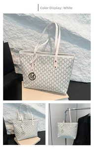 Macro shot of white tote bag with M-pattern print and metallic charm detail
