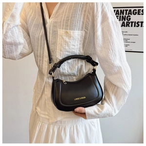Detail of black leather handbag with knotted handle and gold brand logo on model