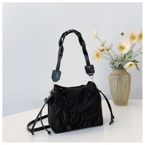 Close-up of black ruched bucket bag with braided handle and drawstring texture detail