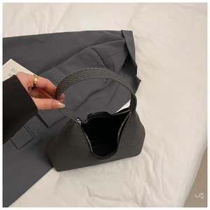 Gros plan du sac à main gris foncé à texture tressée sur fond de tissu avec main