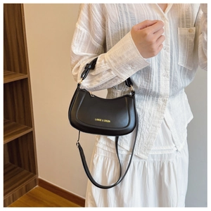 Detail of black PU leather saddle bag with gold logo and knotted handle detail