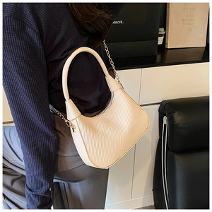 Detail of beige woven baguette bag with gold chain strap and modern minimalist design